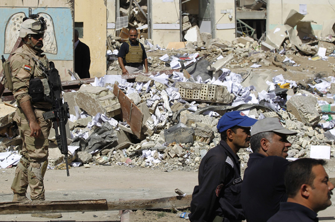 Iraqi security inspect the site of a bomb attack in Baghdad.  (Photo Courtesy of Al-Jazeera)