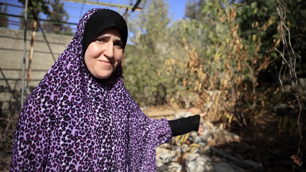 Enas Taha shows her garden, which has turned brown due to the severe water shortages since June [Eloise Bollack/Al Jazeera]
