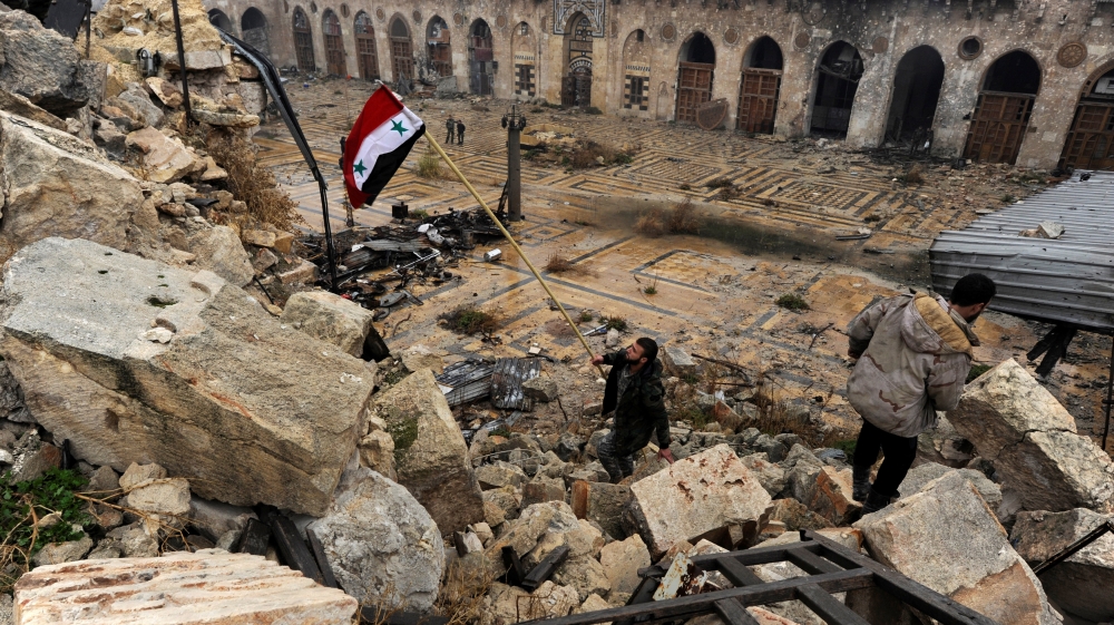 Un soldato siriano sventola la bandiera nazionale sulle macerie della moschea degli Omayyadi ad Aleppo. Credits to: Omar Sanadiki/Reuters