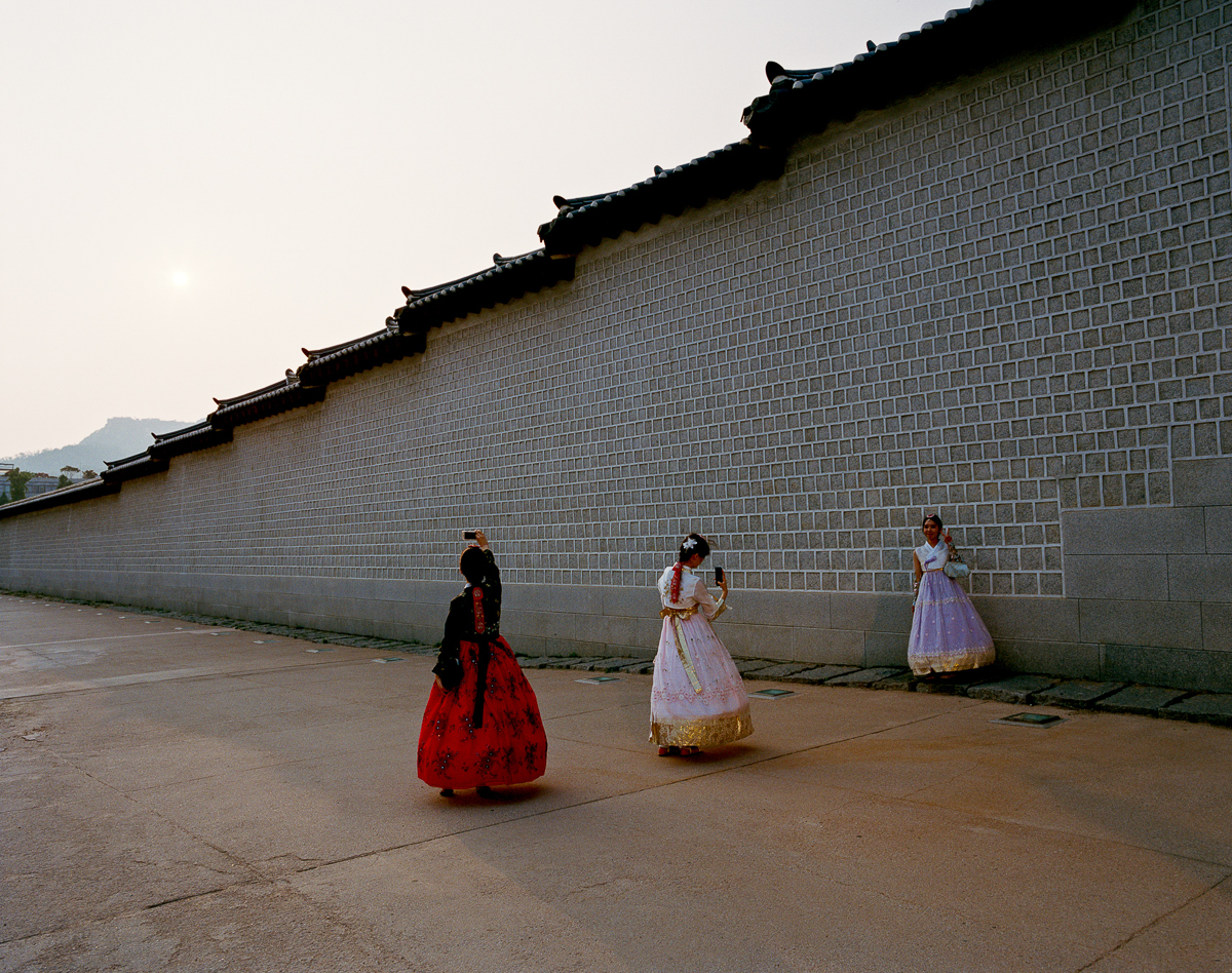 Young women are posing for pictures in front of the Gyeongbokgung-Palace (built in 1395) wearing a Hanbok, Korea's traditional attire, which dates back to the Joseon era (from 1392-1910). In 1427, the Joseon dynasty issued a royal decree banning the performance of Islamic rituals and Muslim traditional attire, as part of an isolationist policy meant to limit contact with foreign countries. [Radu Diaconu/Al Jazeera]