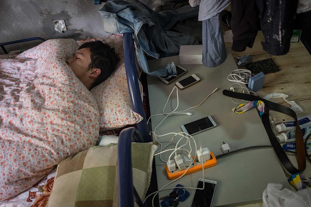 A bitcoin miner rests in his dormitory at a bitcoin mine. 'The good thing is, there isn't anywhere to spend money, so you can save your whole salary,' bitcoin miner Sun says. [EPA/Liu Xingzhe/CHINAFILE]