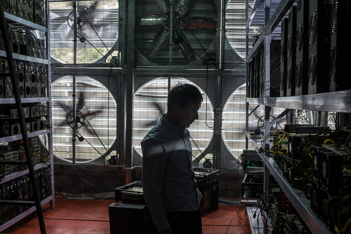Bitcoin mine owner Liu, 29, stands in front of a wall of cooling fans at his mine where he houses and operates mining machines for those who do not want to move to rural Sichuan. [EPA/Liu Xingzhe/CHINAFILE]