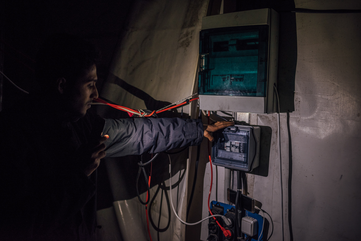 A Syrian refugee is showing the main electricity switch inside a larger tent, hosting hundreds of people. 'There is no electricity here for weeks and in here it is often colder than outside,' he said. [Kevin McElvaney/Al Jazeera]