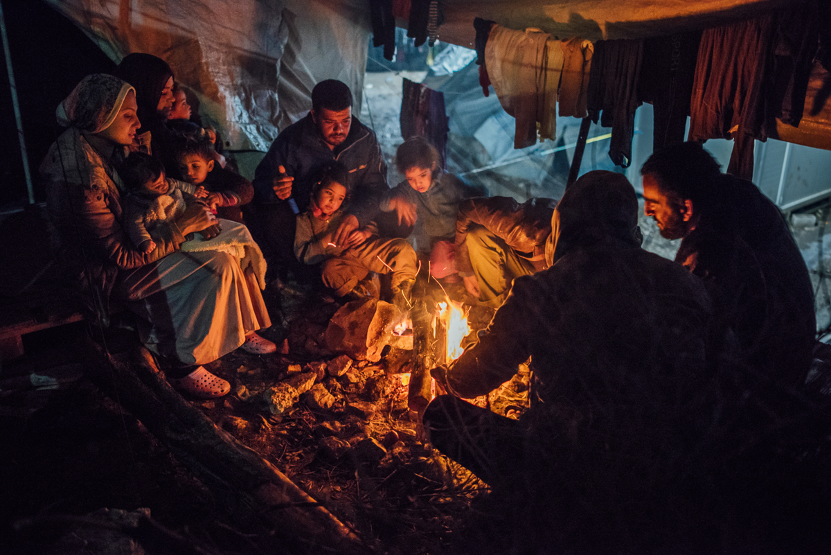 Syrian and Iraqi asylum seekers share a fireplace between their tents. For many Moria camp residents, this is the only way to protect themselves from the plummeting winter temperatures. [Kevin McElvaney/Al Jazeera]