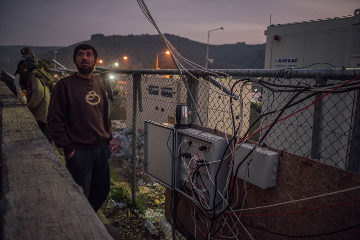 An asylum seeker is making tea at one of the camp's rare functioning electricity spots. The network often collapses and people do not have access to power for days. [Kevin McElvaney/Al Jazeera]