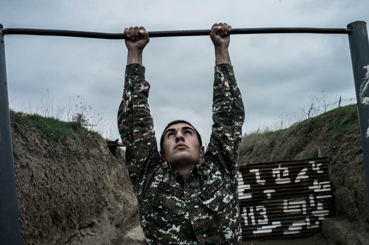 A conscript does pull-ups in a trench at a frontline position. There is little space to move around within the soldiers' barracks, as the positions are closely monitored by the opposite side. [Gus Palmer/Al Jazeera]
