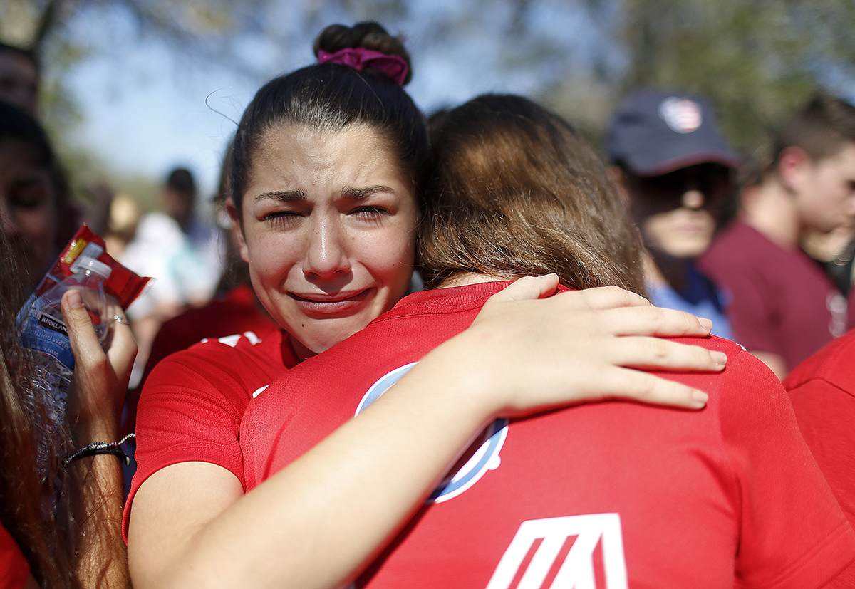 A student mourns the loss of her friend during a community for the victims of the shooting at Marjory Stoneman Douglas High School in Parkland, Florida. Nikolas Cruz, a former student, was charged with 17 counts of premeditated murder on Thursday. [Brynn Anderson/AP Photo]