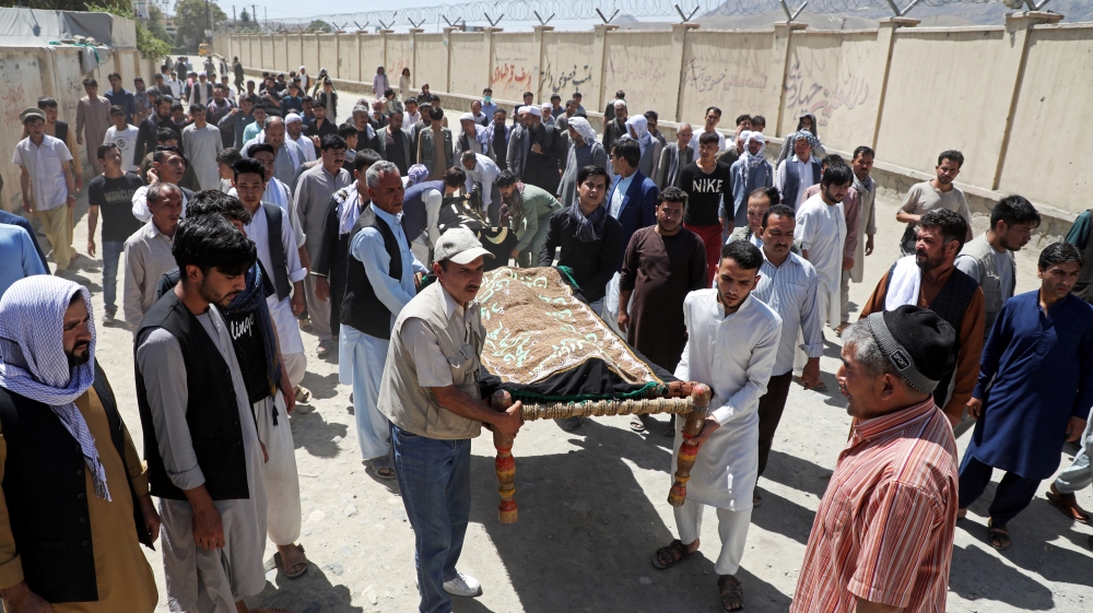 Afghan men carry the bodies of the victims during a mass funeral after a suicide bomb blast at a wedding in Kabul