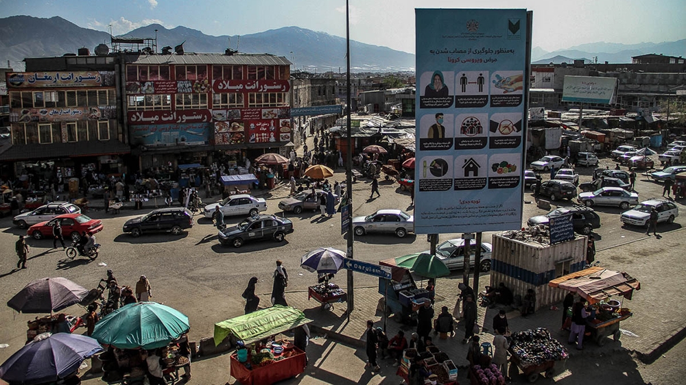 A sign with anti-coronavirus measures over a busy bazaar in Kabul  [Agnieszka Pikulicka-Wilczewska/Al Jazeera]