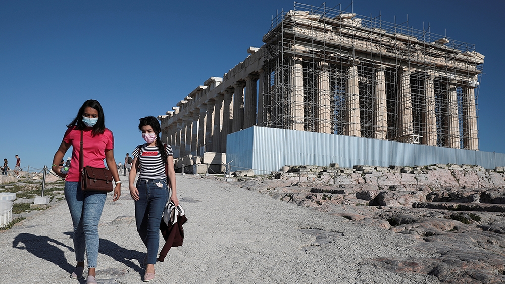 Visitors wear protective face masks as they walk past the ancient Parthenon temple at the archaeological site of the Acropolis in Athens, Greece, March 13, 2020. REUTERS/Costas Baltas