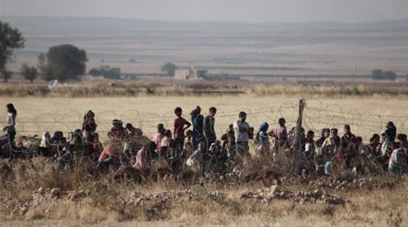Syrians wait near the Turkish border during clashes between ISIL and Kurdish YPG fighters [Getty Images]
