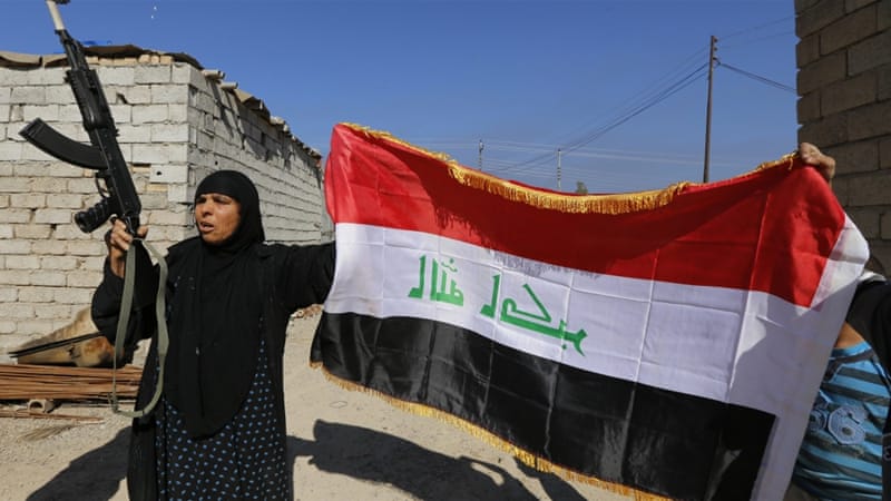 A woman with a weapon and the Iraqi flag in the town of al-Alam [Reuters]