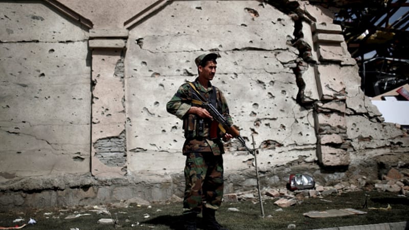 A member of the Afghan security force in front of a damaged building a day after attacks outside the Afghan parliament [REUTERS]