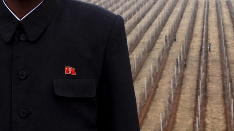 An official of Daedonggang Fruit Farm poses wearing a lapel badge featuring North Korea founder Kim Il-sung [AP]