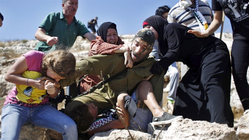 Palestinians scuffle with an Israeli soldier as they try to prevent him from detaining a boy in the village of Nabi Saleh [REUTERS]