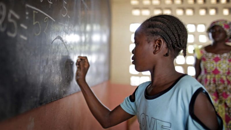 A girl working out sums at the blackboard during a math lesson at a refugee camp in Bangui [Getty]