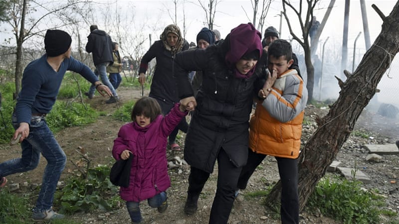 A woman holds her children as they run away after Macedonian police fired tear gas [Giannis Papanikos/AP]