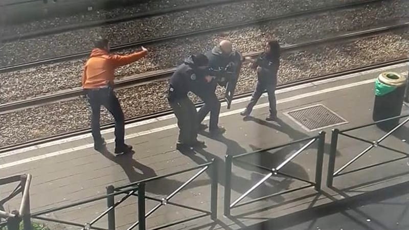 An image showing police as they coax a young girl away from a suspect who is laying on the ground at a tram stop in Brussels on Friday [AP]