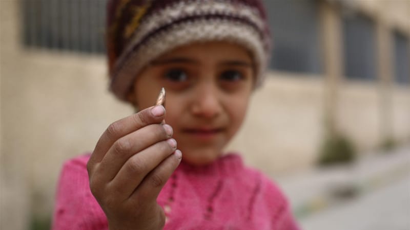 A girl shows a sniper bullet that was found in the school yard in the rebel-held city of Douma, on the outskirts of Damascus, Syria [EPA]