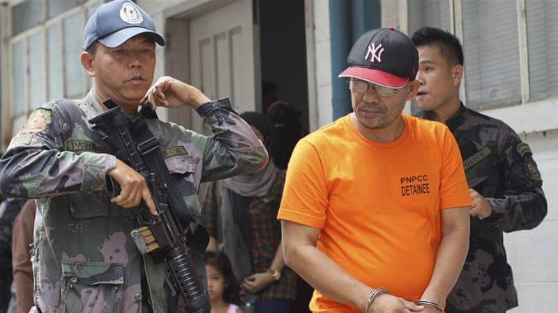 In this June 2014 photo, a Philippine police officer escorts Abu Sayyaf commander Khair Mundos from court [Mark Cristino/AP]