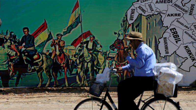 A man rides a bike near a mural supporting the referendum for independence of the Kurdish region in Erbil, Iraq [Alaa Al-Marjani/Reuters]