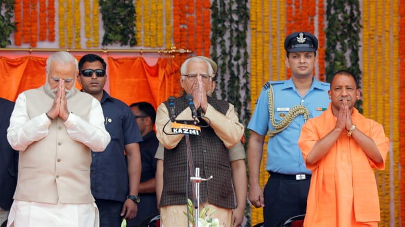 Narendra Modi, left, Uttar Pradesh governor Ram Naik and Yogi Adityanath, right, greet a gathering before Adityanath takes an oath as the new leader of Uttar Pradesh on March 19 [Pawan Kumar/Reuters]