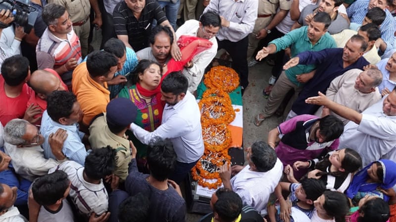 La gente se reúne para presentar sus respetos al lado de un ataúd que contenía el cuerpo de un oficial de la CRPF, que fue muerto en una emboscada maoísta en la India en abril [Sanjay Baid / EPA]