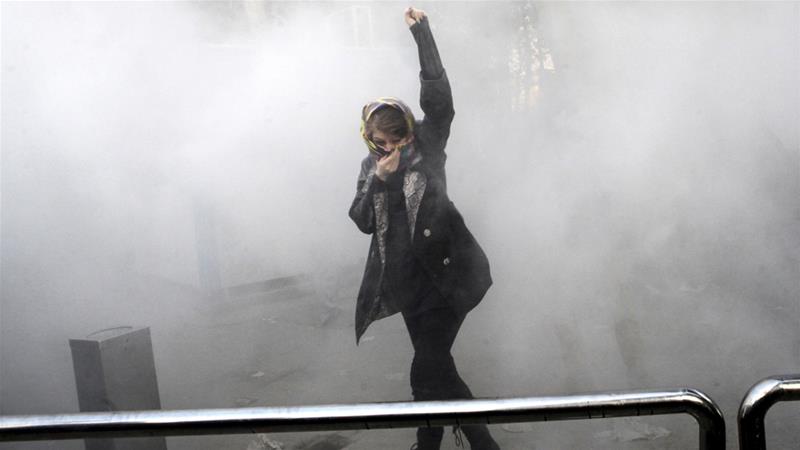 Un estudiante universitario asiste a una protesta dentro de la Universidad de Teherán mientras la policía iraní arroja una granada de humo en Teherán, Irán, el 30 de diciembre de 2017 [AP]