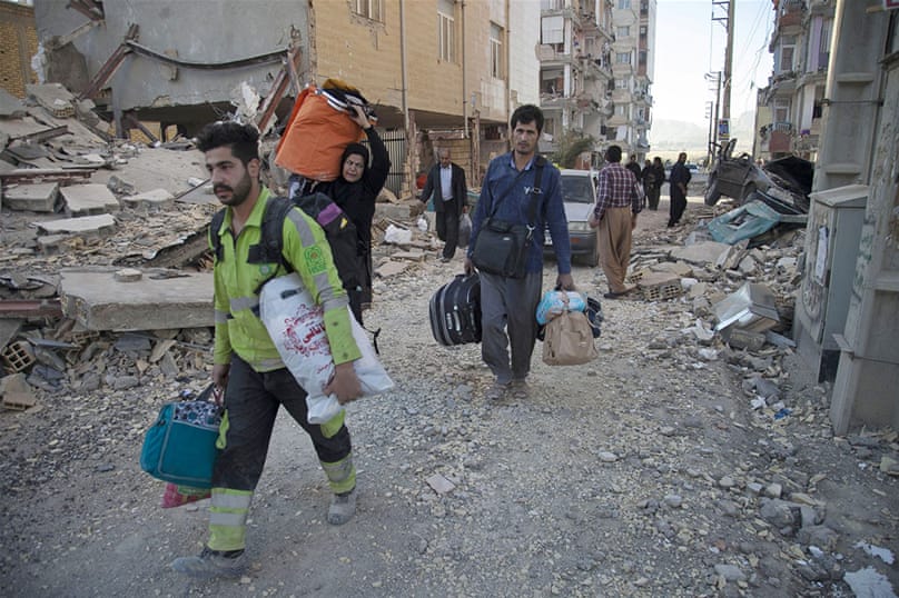 La gente lleva sus pertenencias después del terremoto.  [Farzad Menati / agencia de noticias Tasnim / AP]