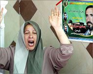 A relative grieves beside a poster of Hamas leader Abu Shanab 