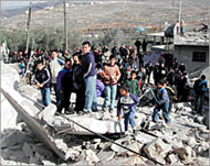 Palestinian children climb over the rubble of a demolished house 