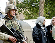 Two students pass a US soldier on guard at Baghdad University 