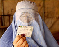 A woman displays her voter registration card in Mazar-i-Sharif