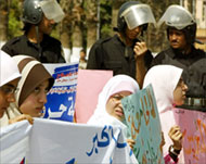 Female students hold signs next to police at Cairo University 