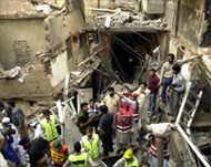Rescue workers stand on the debris of a building in Lahore