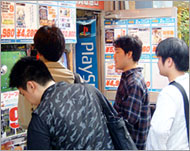 Otaku try out a new computergame on a street in Akihabara