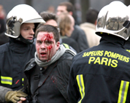 An injured protester is taken away by firemen in Invalides