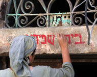 A settler chalks the words'Shapira's house' across a sill