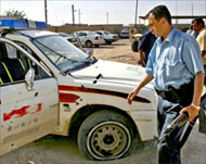 An Iraqi policeman inspects a destroyed police car in Kirkuk