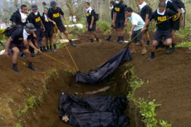 Soldiers bury unidentified bodies at a mass grave for recovered bodies from the devastated Guinobatan town 02 December 2006.
