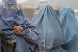 Afghan widows wearing a traditional burqa line up to receive month ration on Thursday 16 November 2006