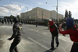 Youth throws stones towards riot police in front of the parliament in Athens