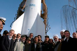 Iranian president Mahmoud Ahmadinejad (C) surrounded by officials, stands under a rocket carrying its first locally made research satellite from a an unknown space centre in Iran on 04 February 2008.