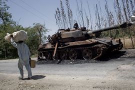 Pakistani displaced by Swat fighting walks past destroyed tank