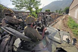 Pakistani army soldiers stand guard on a tank as they cross a street during a military operation in Buner
