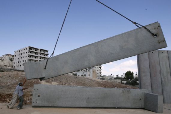 Workers adjust a concrete block lowered by a crane in Shuafat refugee camp