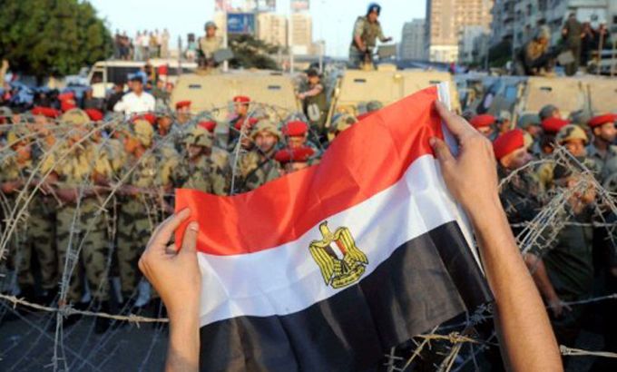 Egyptian soldiers stand behind barbed wire during protests