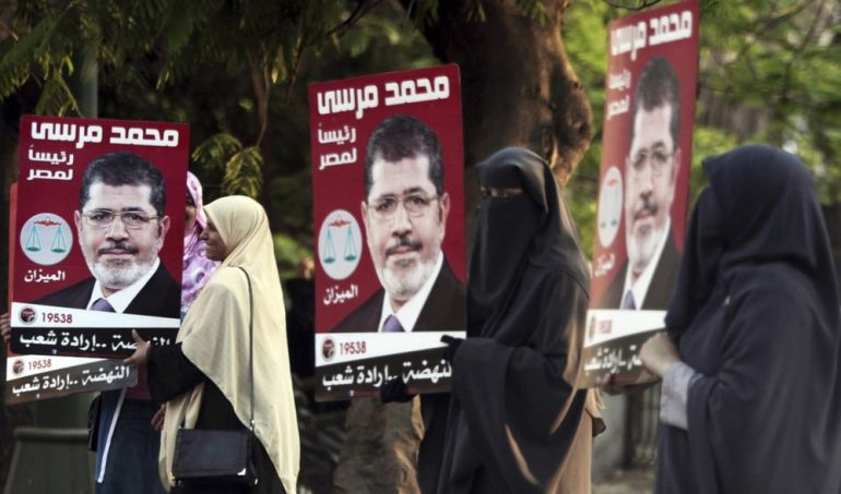 Supporters of Mohamed Mursi hold posters of Mursi during a human chain with participation of party members and supporters of the campaign for the presidency, in Cairo