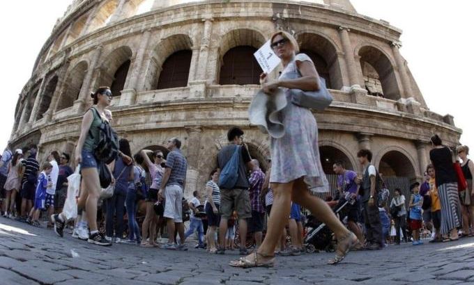 Tourists walk in front of Rome''s ancient Colosseum