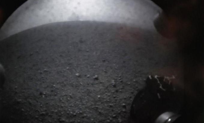 In this image from NASA TV, shot off a video screen, one of the first images from the Curiosity rover is pictured of its wheel after it successfully landed on Mars